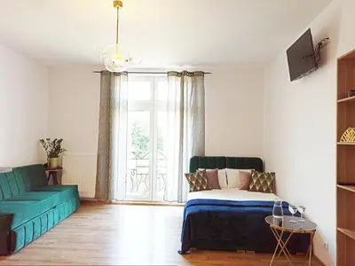 a living room with a bed and a couch and a window at Wieliczka City Apartments in Wieliczka