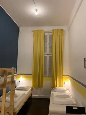 a bedroom with two beds and a window with yellow curtains at VIKI Kazimierz in Kraków
