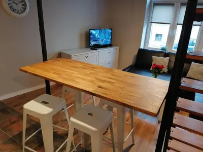 a dining room with a wooden table and two stools at Studio Krakow old town apartment in Kraków