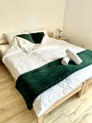 a bed with a green and white blanket on it at Land House in Zator