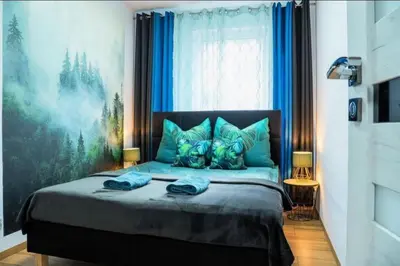 a bedroom with a bed with blue pillows and a window at Apartament Glamour Kraków in Kraków