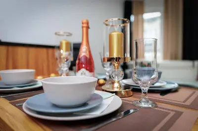a table with a bowl and plates and wine glasses at Apartament Glamour Kraków in Kraków