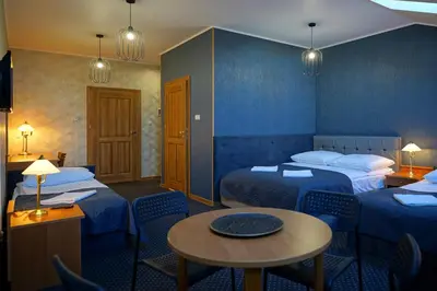 a hotel room with two beds and a table and chairs at Apartments ALKANTARA in Chrzanów