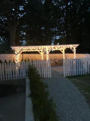 a white fence with a pergola with lights on it at Tramonto Apartments Zator Przeciszów in Zator