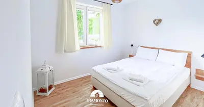 a white bedroom with a large bed with a window at Tramonto Apartments Zator Przeciszów in Zator
