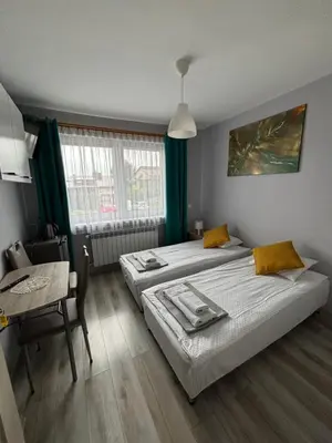 a bedroom with two beds and a table and a table and a chair at Noclegi u Tadka in Zator