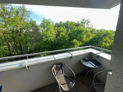 a balcony with a table and a chair and trees at Apartament 6 piętro in Kraków