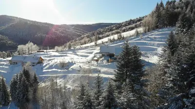 a snow covered mountain with a house in the distance at Gorczańskie Zacisze in Lubomierz