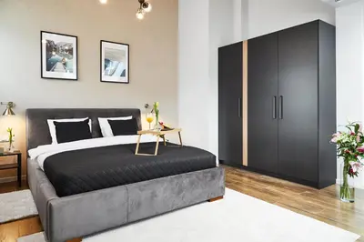 a bedroom with a large bed and a black cabinet at Szpitalna 9 Residence in Kraków