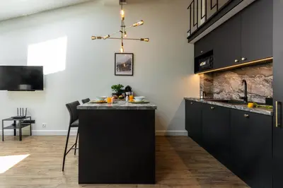 a kitchen with black cabinets and a large island at Szpitalna 9 Residence in Kraków