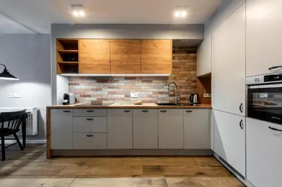 a kitchen with white cabinets and a brick wall at Szpitalna 9 Residence in Kraków