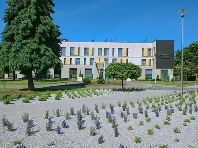 a building with a garden of flowers in front of it at Hotel Olimpijski in Oświęcim