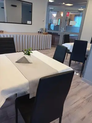 a dining room with a table and chairs and a screen at Hotel Olimpijski in Oświęcim