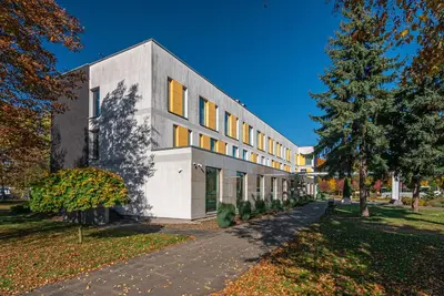 a white building with yellow windows on a street at Hotel Olimpijski in Oświęcim