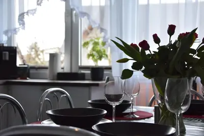 a table with a vase of flowers and wine glasses at Apartament Night Premium Krakow in Kraków