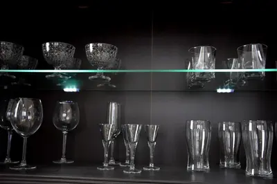 a row of wine glasses on a shelf with lights at Apartament Night Premium Krakow in Kraków