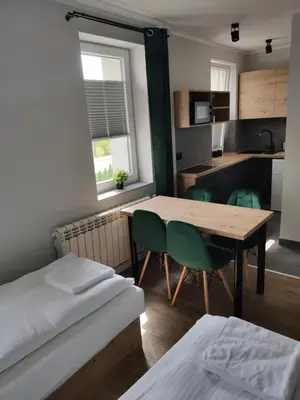 a room with a table and chairs and a kitchen at Krollhouse Pokoje gościnne in Wolbrom
