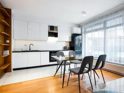 a kitchen with white cabinets and a glass table and chairs at Golden Queen Apartments Jewish District in Kraków