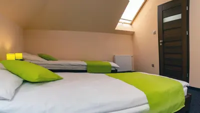 two beds in a room with green and white sheets at Pokoje Gościnne z łazienkami in Niepołomice