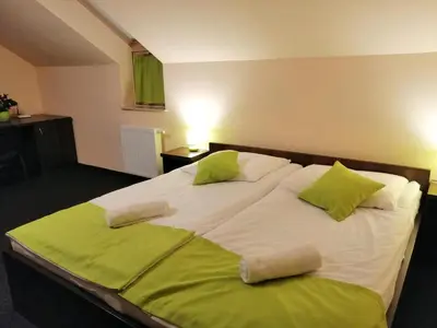 a large bed with two green pillows on it at Pokoje Gościnne z łazienkami in Niepołomice