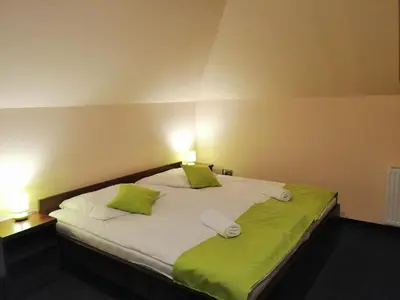 a large bed with green and white sheets and pillows at Pokoje Gościnne z łazienkami in Niepołomice