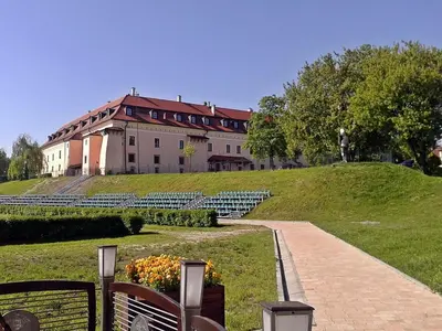 a large building on top of a green hill at Pokoje Gościnne z łazienkami in Niepołomice