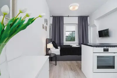 a living room with a kitchen and a couch at Studios Lubelska Kraków by Noclegi Renters in Kraków