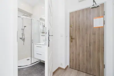 a bathroom with a shower and a wooden door at Studios Lubelska Kraków by Noclegi Renters in Kraków