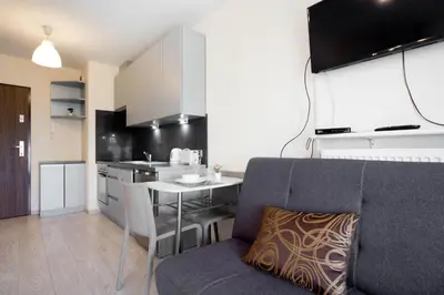 a kitchen and dining room with a couch and a table at Cozy modern Apartment ASTORIA MAGIC GREY OLD TOWN in Kraków