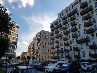 a parking lot with cars parked in front of a tall building at Cozy modern Apartment ASTORIA MAGIC GREY OLD TOWN in Kraków