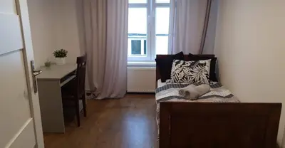 a bedroom with a bed and a desk and a window at Schodami do Nieba in Kraków