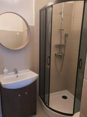 a bathroom with a sink and a shower with a mirror at Schodami do Nieba in Kraków