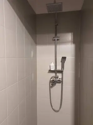 a shower in a bathroom with white tiles at Schodami do Nieba in Kraków