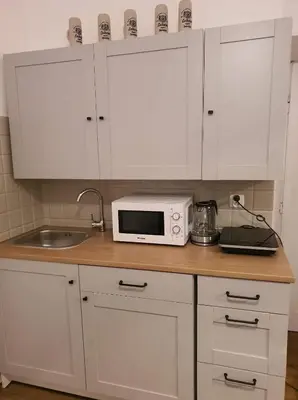 a kitchen with white cabinets and a microwave on a counter at Schodami do Nieba in Kraków