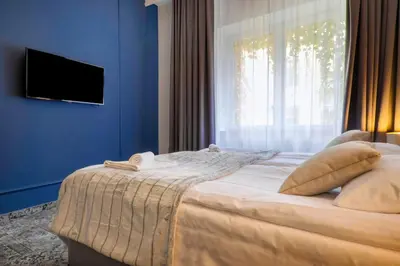a bedroom with a bed with blue walls and a window at Aparthotel Cracovia Residence in Kraków