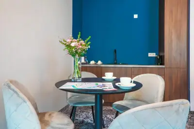 a table with chairs and a vase of flowers on it at Aparthotel Cracovia Residence in Kraków