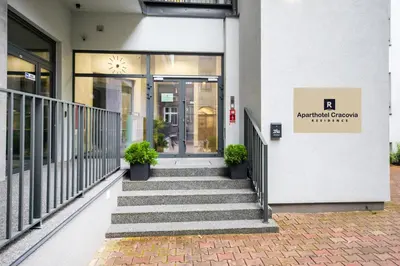 a building with stairs and plants in front of it at Aparthotel Cracovia Residence in Kraków