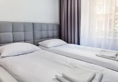 two beds with white sheets and pillows next to a window at Aparthotel Cracovia Residence in Kraków