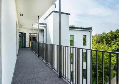 an external walkway of a white building with a black fence at Aparthotel Cracovia Residence in Kraków