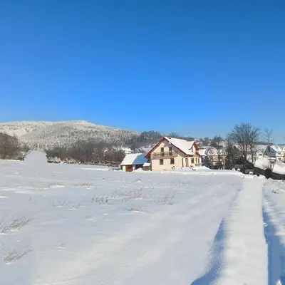 a snow covered field with a house in the distance at Nad Strumykiem in Mszana Dolna