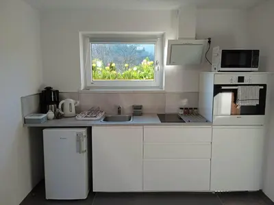 a white kitchen with a sink and a window at Nad Strumykiem in Mszana Dolna