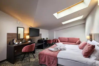 a hotel room with a bed and a desk and a room at Hotel Estera in Kraków
