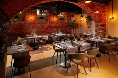 a restaurant with tables and chairs and a brick wall at Hotel Estera in Kraków
