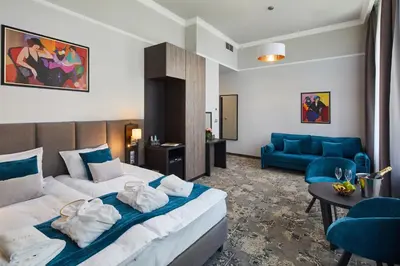 a hotel room with a bed and a blue couch at Hotel Estera in Kraków