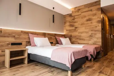 two beds in a room with wooden walls at Hotel Rancho Pcim in Pcim