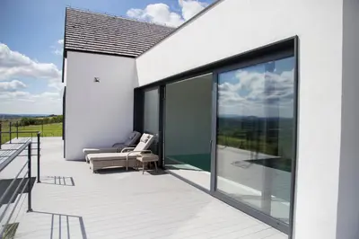 a white house with a balcony with glass doors at villa relax with swimming pool and mountain view in Buków