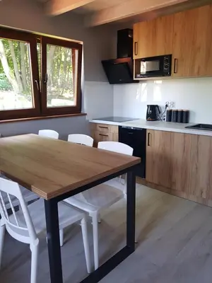a kitchen with a wooden table and white chairs at Kameralny in Przeciszów