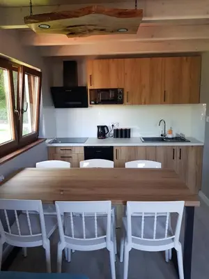 a kitchen with a wooden table and white chairs at Kameralny in Przeciszów