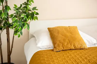 a bed with a yellow pillow and a tree at Cozy modern Apartment ASTORIA MAGIC ORANGE OLD TOWN in Kraków