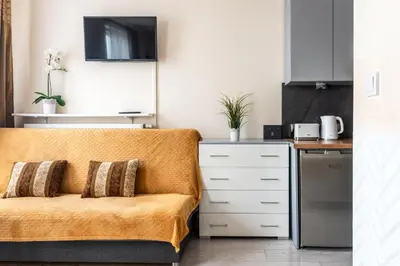 a living room with a couch and a kitchen at Cozy modern Apartment ASTORIA MAGIC ORANGE OLD TOWN in Kraków